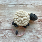 Crochet sheep tape measure laying on wooden table