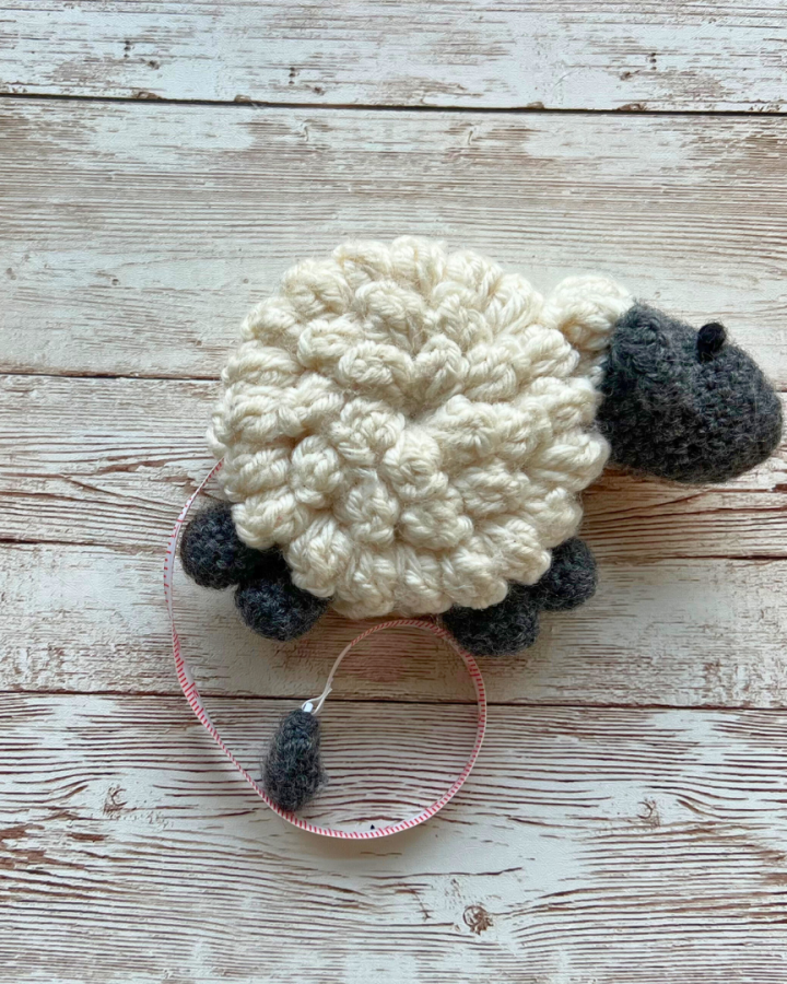 Crochet sheep tape measure laying on wooden table